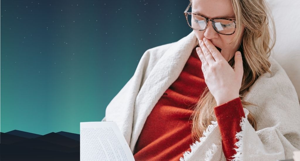 Tired woman yawning while reading