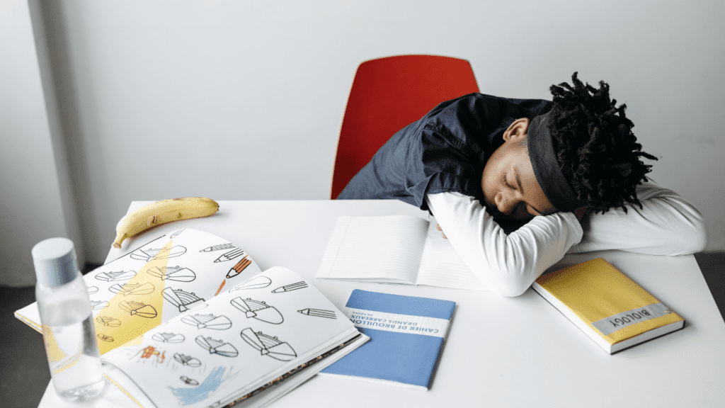 Pre-teen African American sleeping at his desk instead of doing schoolwork because of insomnia